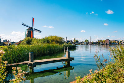 Traditional windmill by canal against sky