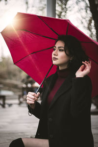 Young woman with umbrella standing in rain