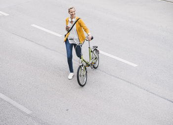 Smiling female professional walking with bicycle on street