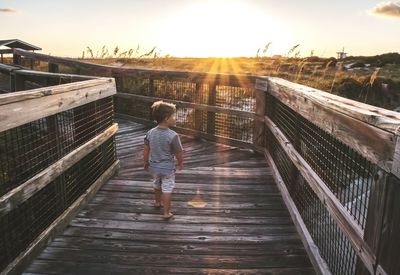 Rear view of boy standing on footbridge