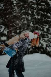 Close-up of woman standing on snow covered tree during winter