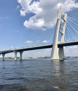 Bridge over calm river against cloudy sky