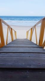 Boardwalk on beach against clear sky