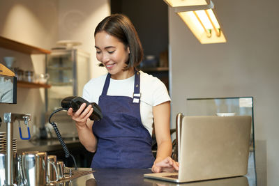 Young woman using mobile phone while sitting at home