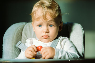 Cute baby girl sitting on stroller at home