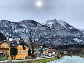 Houses on snowcapped mountain against sky in hallstatt austria 