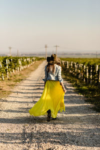 Rear view of woman walking on road