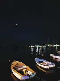 Boats moored at harbor against sky at night