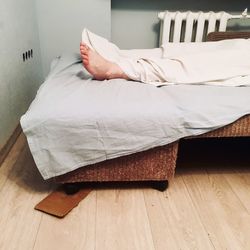 Low section of man relaxing on bed at home