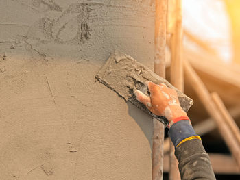 Close-up of hands working on wood against wall