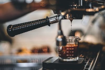 Close-up of coffee pouring from espresso maker in cup