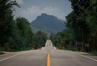 Road amidst trees against mountains