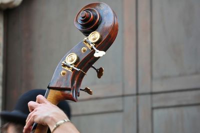 Cropped image of person playing cello against door