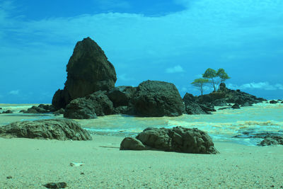 Rocks in sea against blue sky