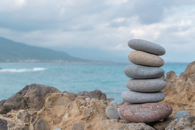 Stack of stones in sea against sky