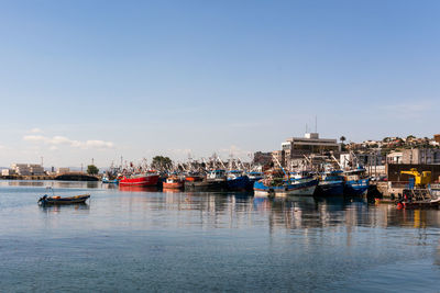 Sailboats moored at harbor against sky