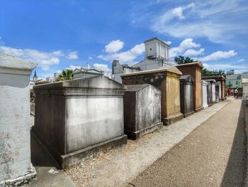 Road by buildings against sky on sunny day