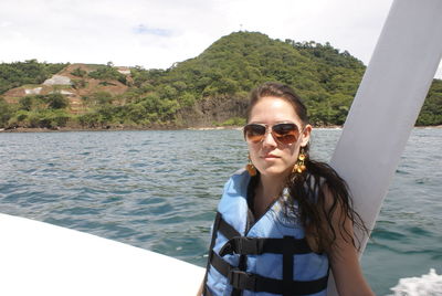 Portrait of smiling young woman in sunglasses against sky