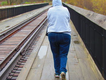 Rear view of person walking by railroad track