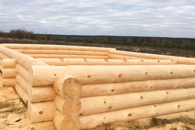 Stack of logs on field against sky