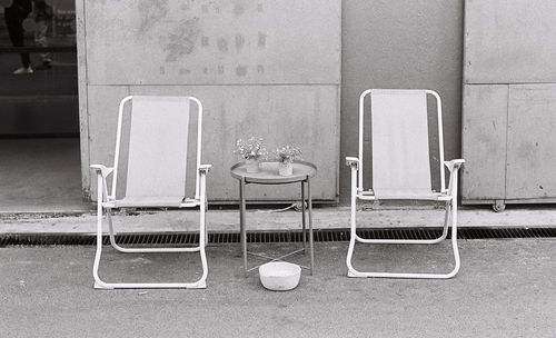 Empty chairs on table against wall