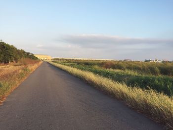 Road amidst field against sky