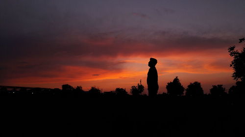 Silhouette man standing against orange sky during sunset