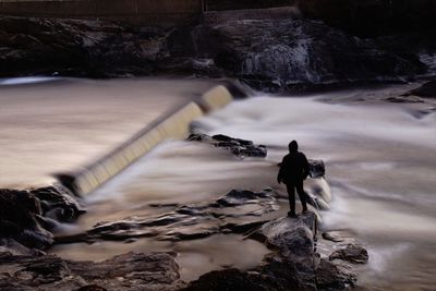 Rear view of man looking at waterfall