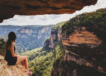 Woman sitting on rock looking at mountains