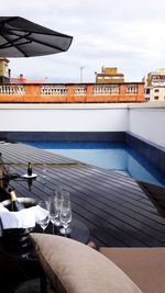 Chairs and tables at swimming pool against sky