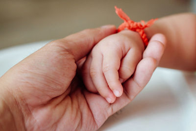 Cropped image of father holding daughter hand at home