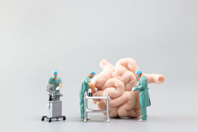 Close-up of figurine with toy against white background