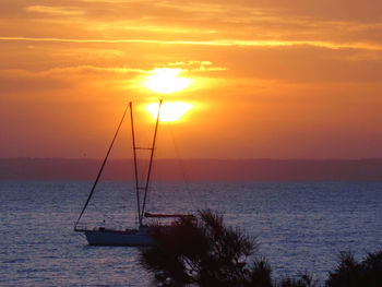 Silhouette sailboat on sea against sky during beautiful  orange sunrise 