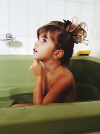 Thoughtful girl sitting in bathtub at bathroom