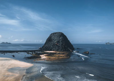 Rock formation on beach against sky