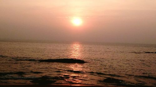 Scenic view of sea against dramatic sky during sunset