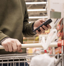 Midsection of man using mobile phone while shopping