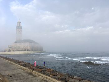 People on beach by sea against sky