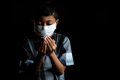 Portrait of a teenage boy covering face