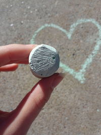 Cropped image of hand holding chalk on footpath