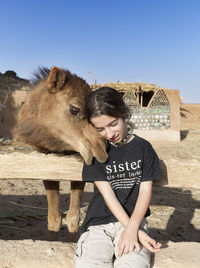 Portrait of twelve year old girl with a dromedary that is giving her love. vertical shot.