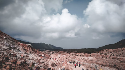 People on rocky mountain against sky