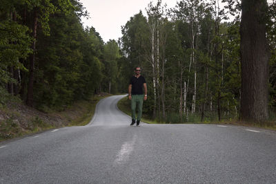 Mid adult man walking on road in forest