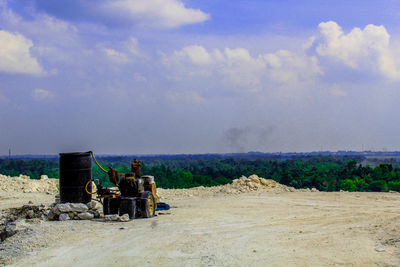 Rear view of men sitting on field against sky