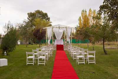 Empty chairs arranged by chuppah at park during wedding ceremony