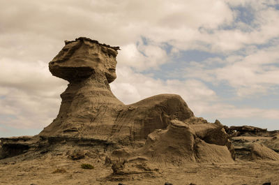 Rock formations on landscape against cloudy sky