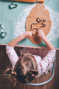 Directly above shot of girl making gingerbread cookie on table