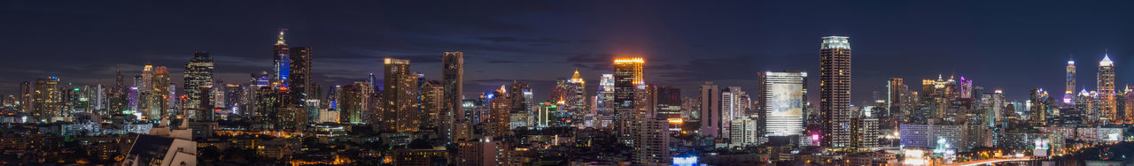 Illuminated modern buildings against sky at night