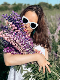 Low angle view of woman wearing sunglasses against pink flowering plants