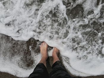 Low section of person standing in sea